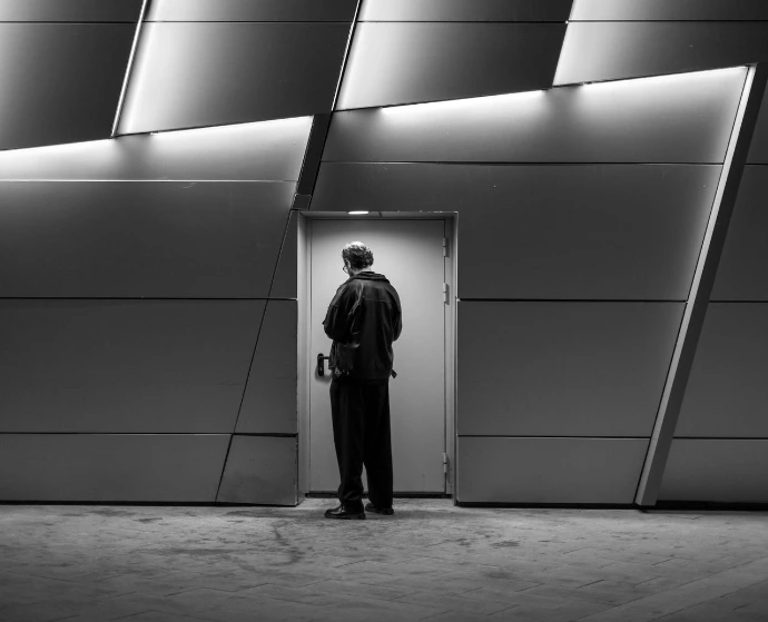 Man in suit stands before modern building entrance